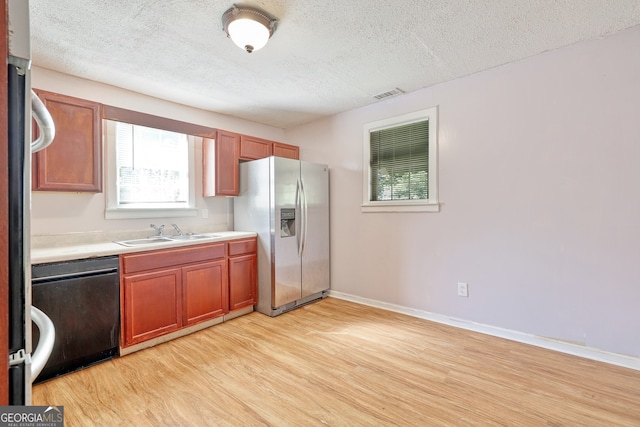 kitchen featuring a textured ceiling, dishwashing machine, light wood finished floors, and stainless steel fridge with ice dispenser