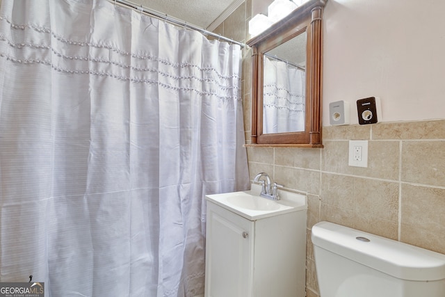 bathroom with tile walls, toilet, vanity, and a shower with curtain