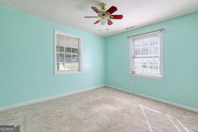 empty room featuring visible vents, carpet floors, a textured ceiling, and ceiling fan