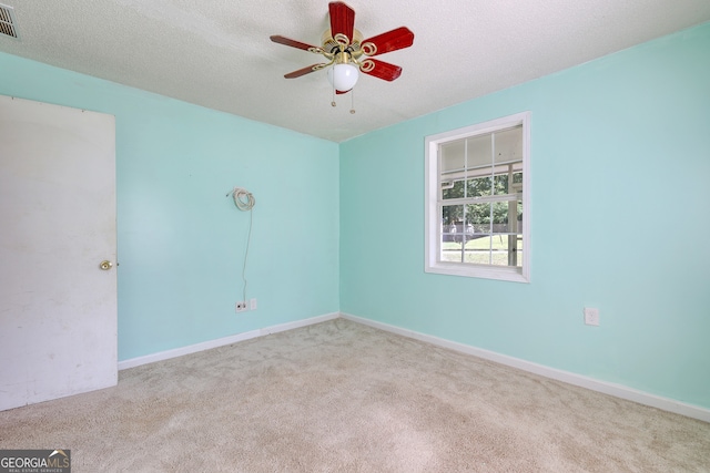 carpeted empty room featuring baseboards, visible vents, a textured ceiling, and ceiling fan