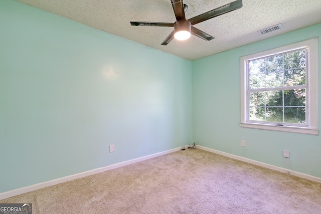 spare room featuring visible vents, carpet floors, baseboards, a textured ceiling, and ceiling fan