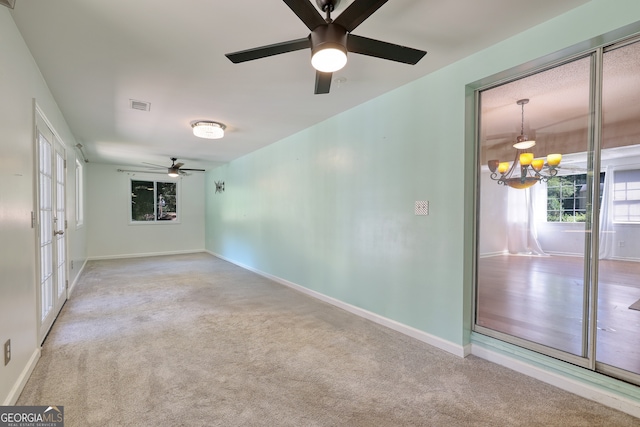 empty room featuring ceiling fan with notable chandelier, plenty of natural light, baseboards, and visible vents