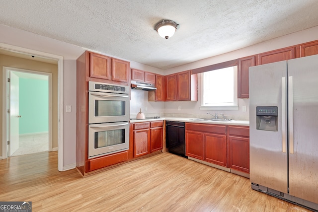 kitchen with sink, a textured ceiling, black appliances, and light wood-type flooring