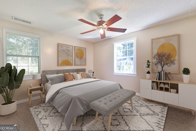 bedroom with baseboards, carpet flooring, a textured ceiling, and visible vents