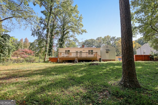 rear view of house featuring a lawn, fence, and a deck