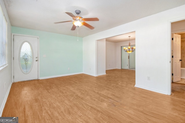 entryway featuring light wood finished floors, baseboards, and ceiling fan with notable chandelier