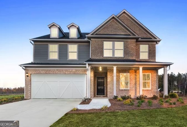 view of front of property featuring a porch, a front lawn, and a garage