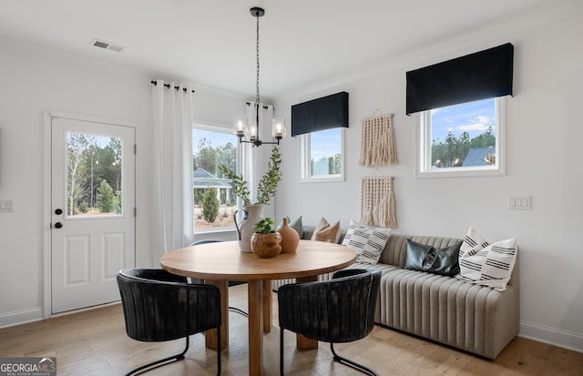 dining space with light hardwood / wood-style floors and a notable chandelier