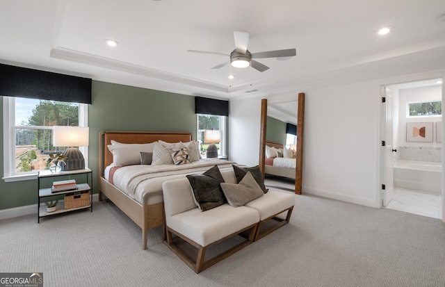 bedroom featuring ceiling fan, connected bathroom, a raised ceiling, and light carpet