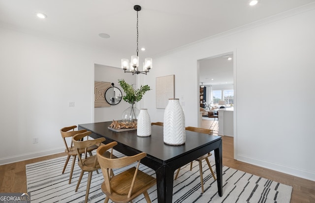 dining space with a notable chandelier, crown molding, and hardwood / wood-style flooring