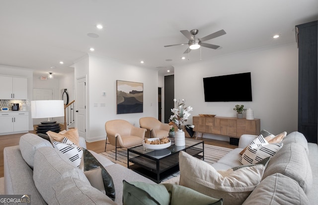 living room featuring light wood-type flooring, ceiling fan, and crown molding