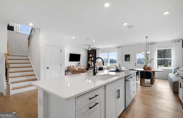 kitchen featuring pendant lighting, a center island with sink, light wood-type flooring, white cabinets, and sink