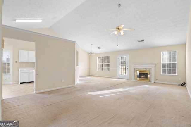 unfurnished living room featuring a high end fireplace, a textured ceiling, vaulted ceiling, and light colored carpet