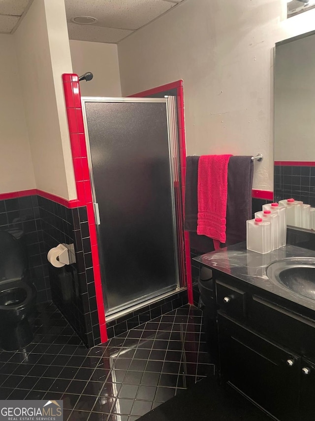 bathroom with a paneled ceiling, a shower with door, vanity, and tile patterned floors