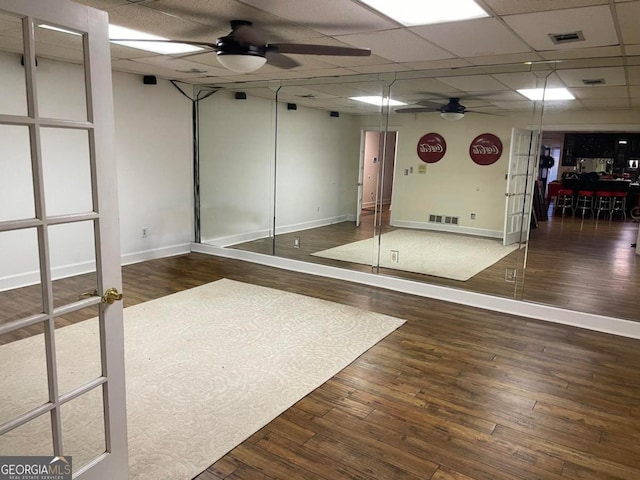 interior space with ceiling fan, a paneled ceiling, and dark wood-type flooring