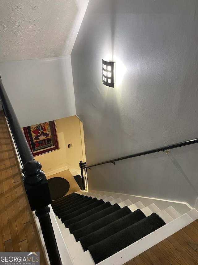 stairs featuring a textured ceiling and wood-type flooring