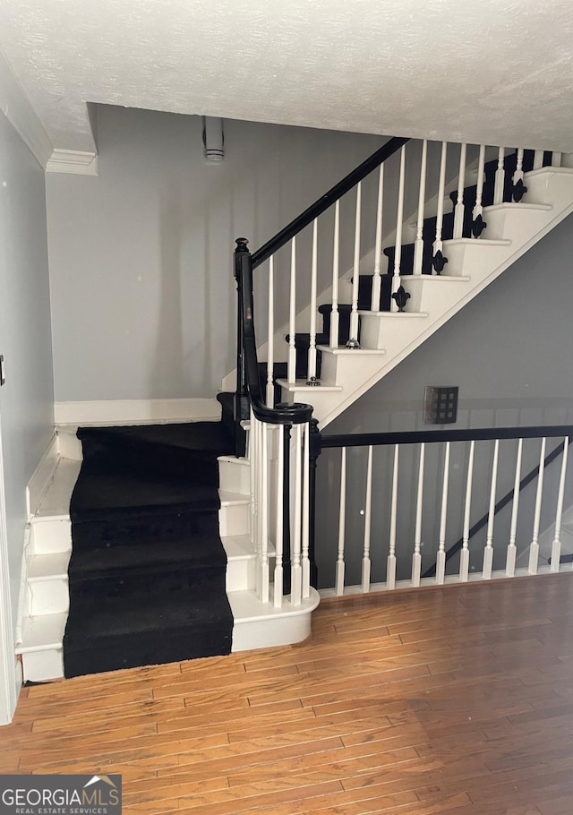 stairs featuring wood-type flooring and a textured ceiling