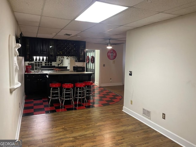 kitchen featuring dark wood-type flooring, a paneled ceiling, and a breakfast bar area