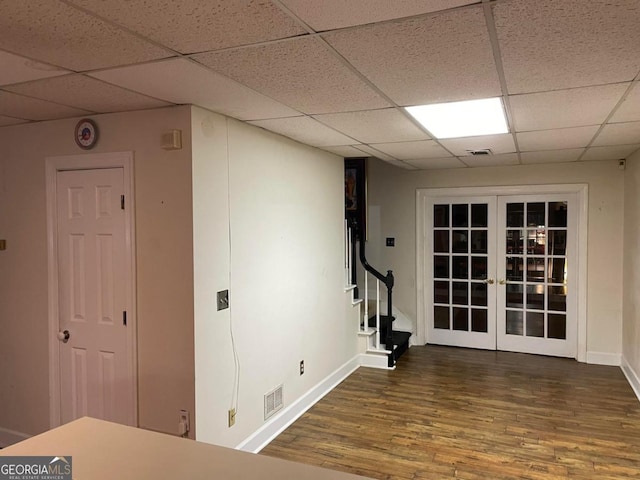 basement with a paneled ceiling, french doors, and dark hardwood / wood-style floors