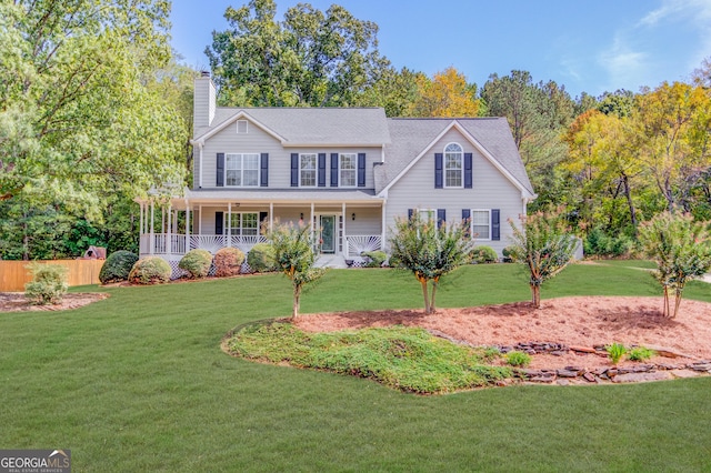 colonial home featuring covered porch, a front lawn, and a chimney