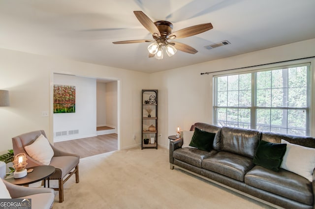 living area with light carpet, baseboards, visible vents, and a ceiling fan