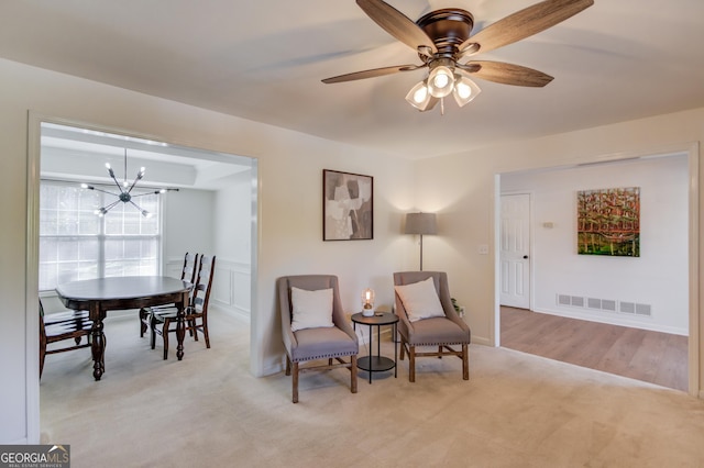 sitting room featuring ceiling fan with notable chandelier, carpet floors, and visible vents