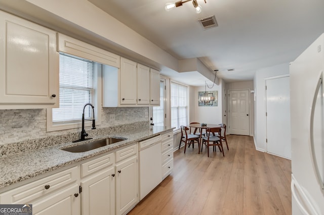 kitchen featuring white appliances, visible vents, a sink, light wood-type flooring, and backsplash