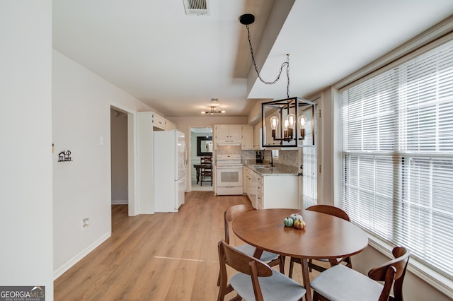 dining area with baseboards, visible vents, a notable chandelier, and light wood finished floors