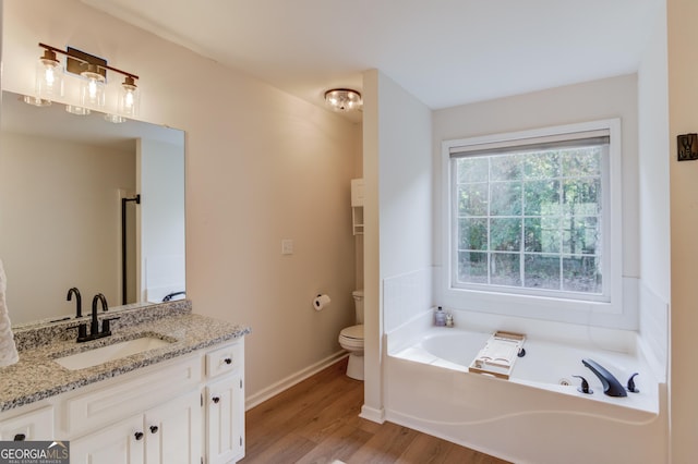 full bathroom featuring a garden tub, toilet, vanity, wood finished floors, and baseboards