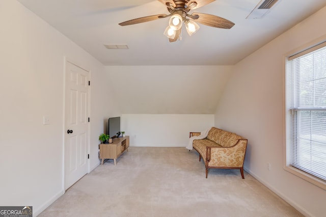 living area featuring light colored carpet, visible vents, a ceiling fan, vaulted ceiling, and baseboards