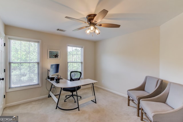 office area with light carpet, a ceiling fan, visible vents, and baseboards