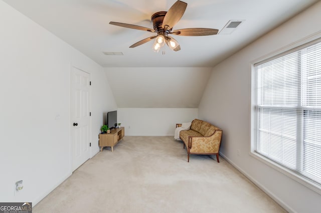 living area with light carpet, ceiling fan, vaulted ceiling, and visible vents