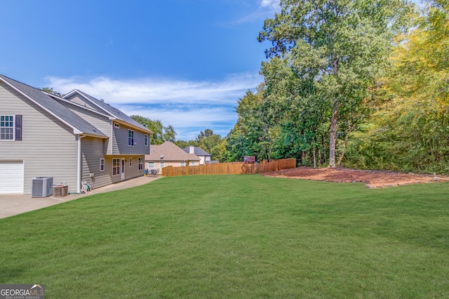 view of yard featuring a garage, a patio area, fence, and central AC unit