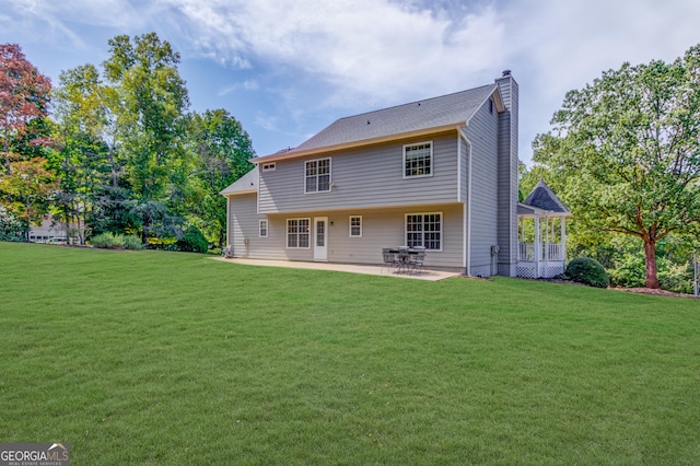 rear view of house featuring a yard, a chimney, and a patio area