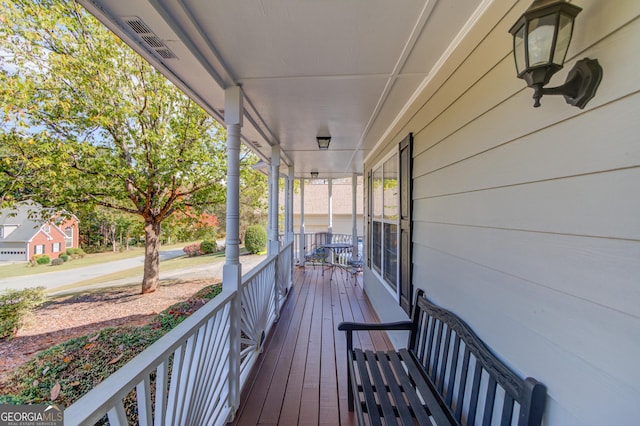 wooden terrace featuring a porch and visible vents