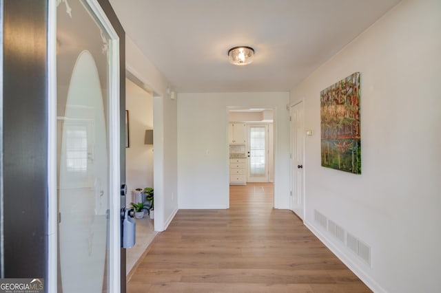 hallway featuring light wood-type flooring, visible vents, and baseboards