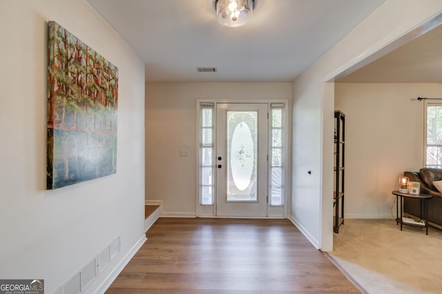 foyer entrance with wood finished floors, visible vents, and baseboards