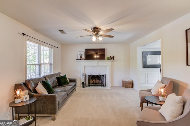 living room with light colored carpet, visible vents, a fireplace with flush hearth, ceiling fan, and baseboards