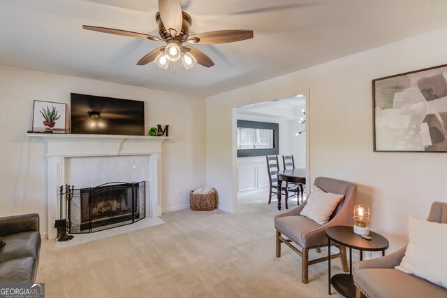 living room featuring carpet, baseboards, a ceiling fan, and a fireplace with flush hearth