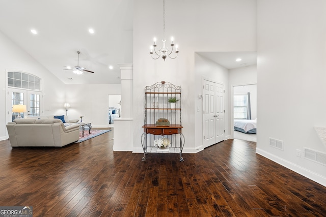 unfurnished living room featuring ceiling fan with notable chandelier, dark hardwood / wood-style flooring, high vaulted ceiling, and a wealth of natural light