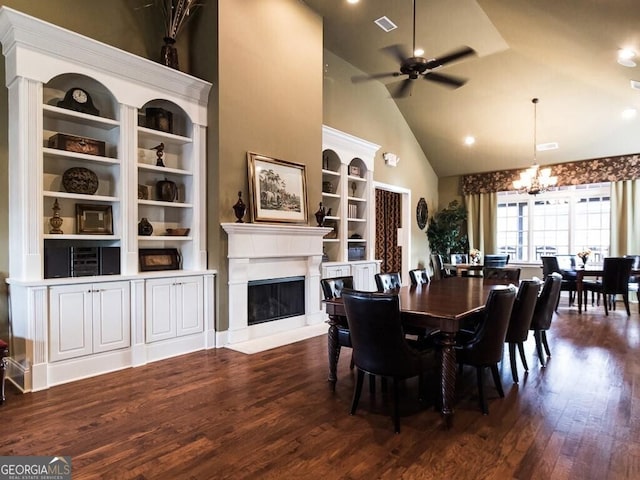 dining area featuring dark wood-type flooring, ceiling fan with notable chandelier, and high vaulted ceiling