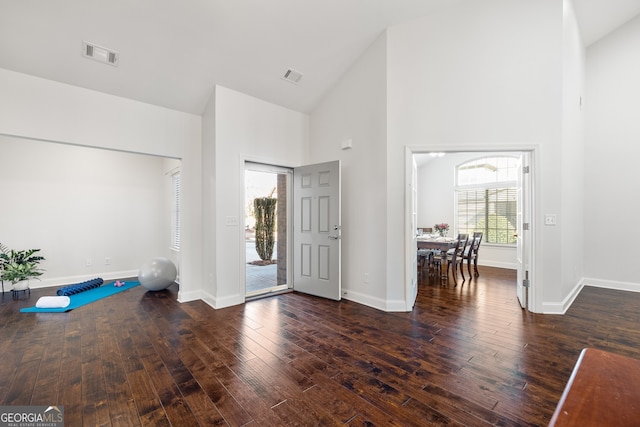 foyer entrance featuring dark wood-type flooring and high vaulted ceiling