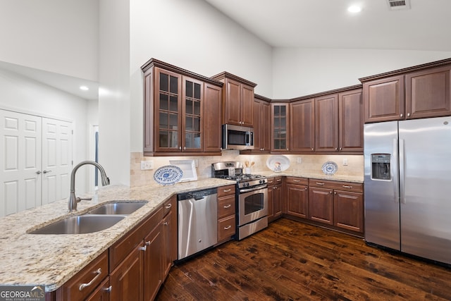 kitchen with sink, light stone counters, appliances with stainless steel finishes, dark hardwood / wood-style flooring, and decorative backsplash