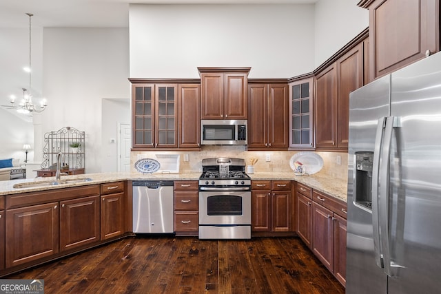 kitchen featuring dark hardwood / wood-style floors, pendant lighting, sink, a high ceiling, and stainless steel appliances