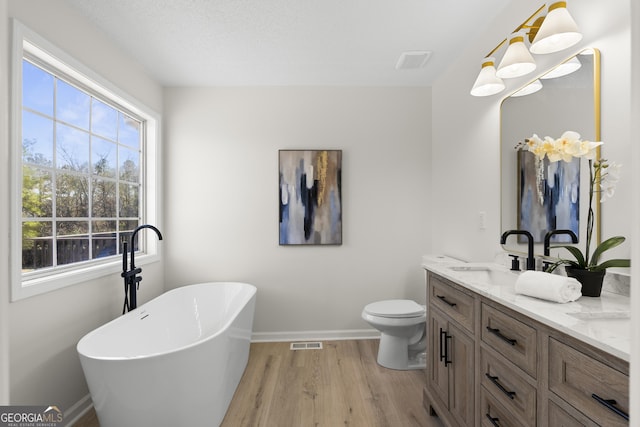 bathroom featuring hardwood / wood-style floors, toilet, vanity, and a bathing tub