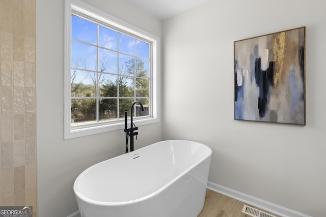 bathroom with wood-type flooring and a tub to relax in