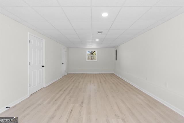 basement featuring light wood-type flooring and a paneled ceiling