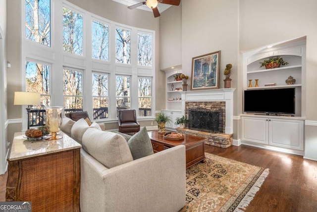 living room with a towering ceiling, a fireplace, and built in features