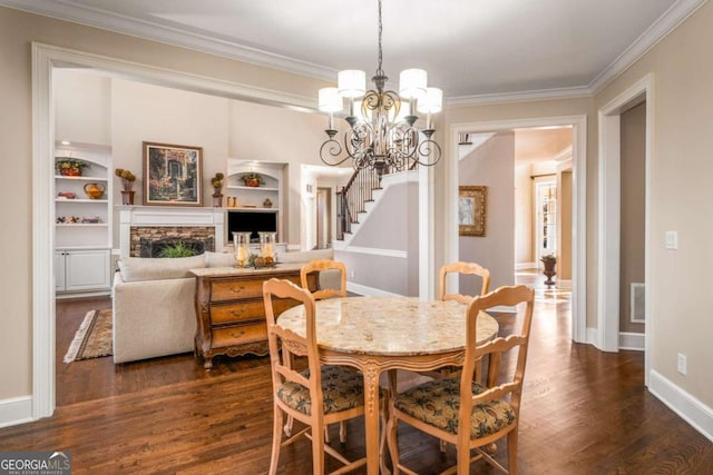 dining space featuring dark wood-type flooring, built in features, a notable chandelier, and ornamental molding