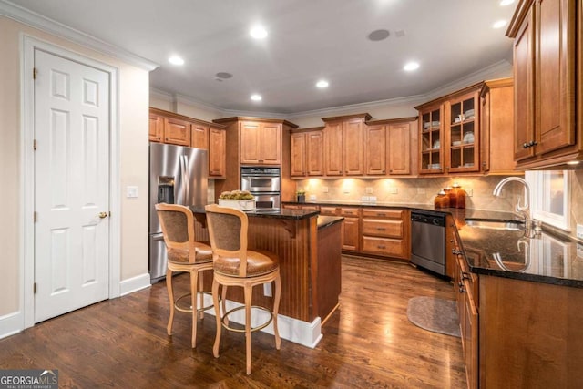 kitchen with dark stone countertops, a breakfast bar area, appliances with stainless steel finishes, a kitchen island, and tasteful backsplash